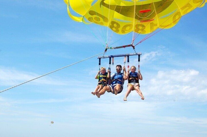 Three people suspended in the air by a parachute. 2