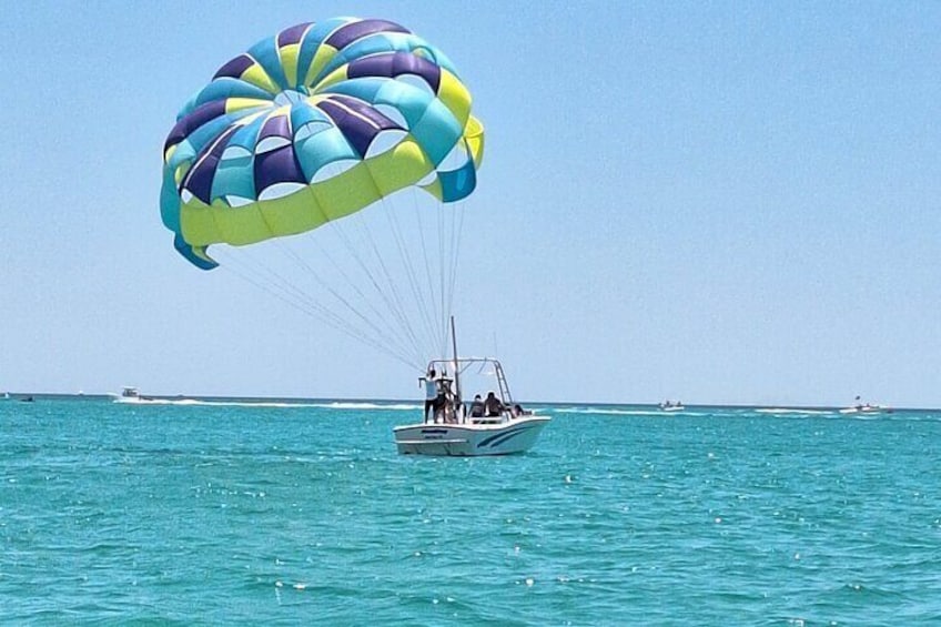 A parasailing boat with a colorful parachute over turquoise waters. 1