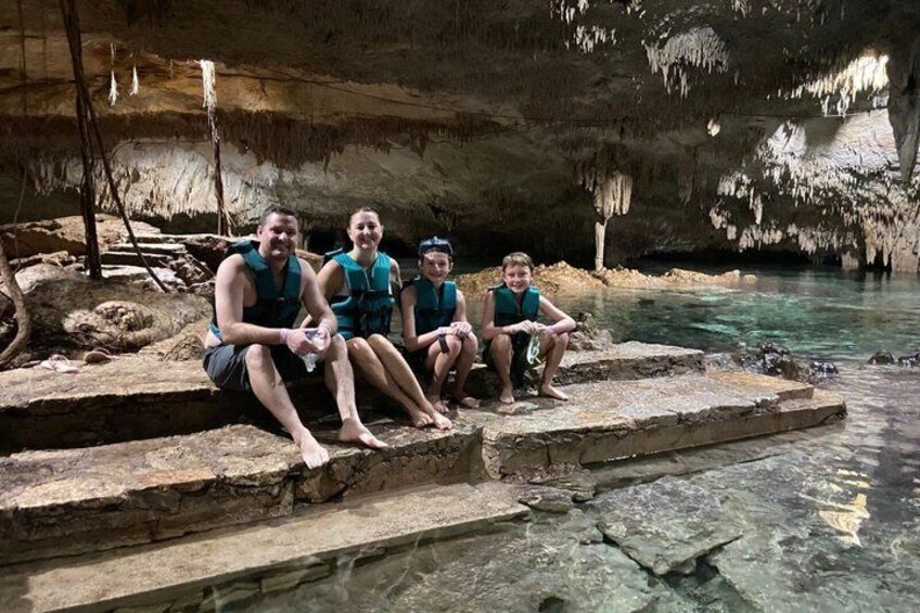 Four people sitting on stone steps in a cave with stalactites. 3