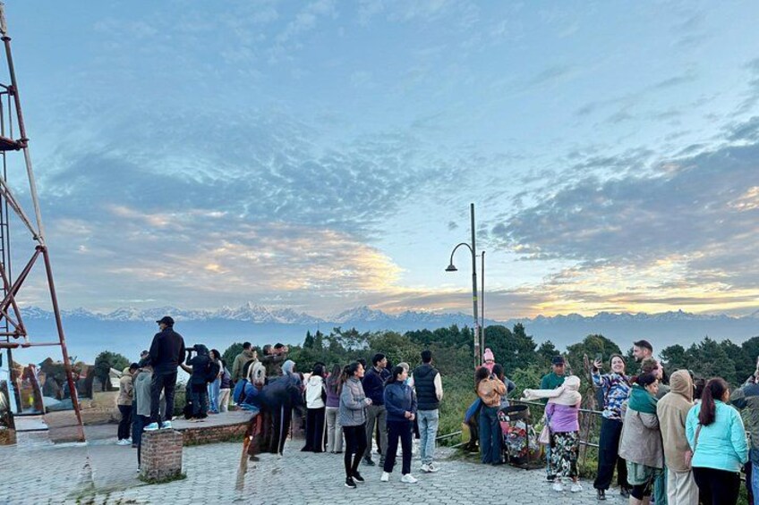 A group of people gathered on a paved area with a mountainous landscape in the background. 4