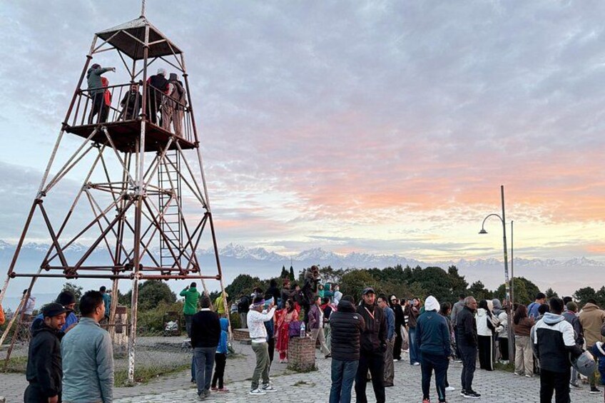 A metal observation tower with people around it, a mountainous landscape, and a sunset sky. 5