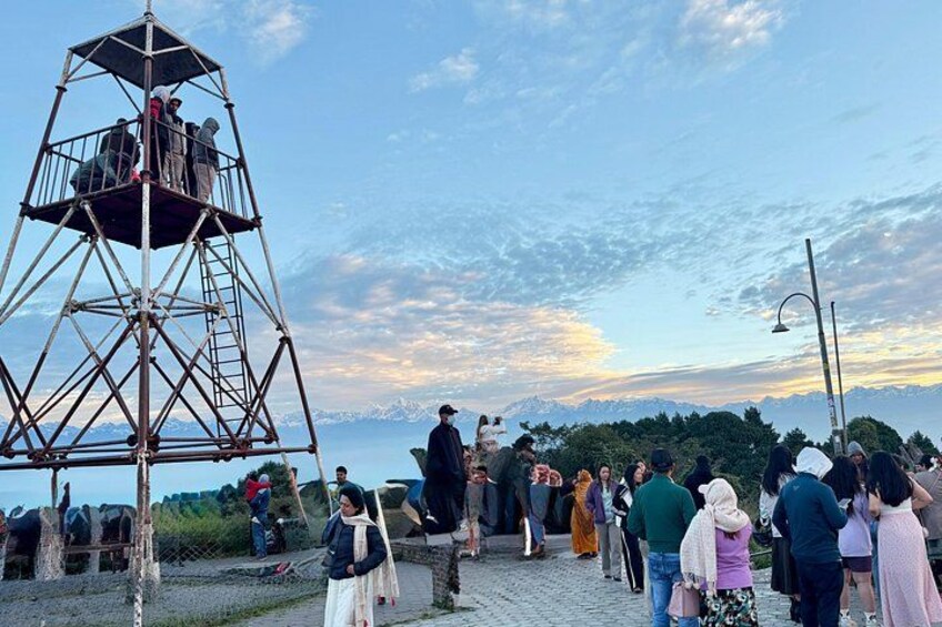 A metal observation tower, a crowd of people, and a mountainous landscape in the background. 3