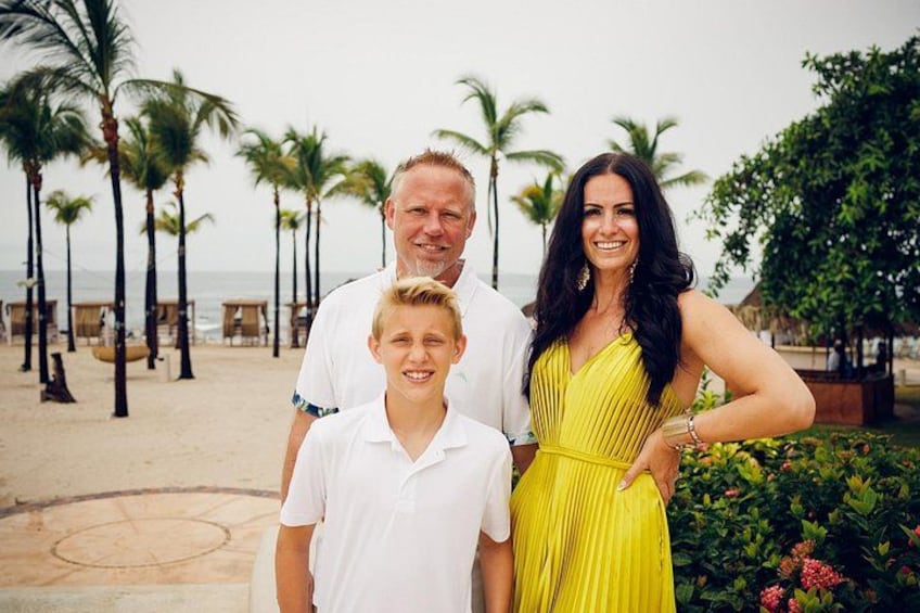 A family on a beach with palm trees and ocean in the background. 5