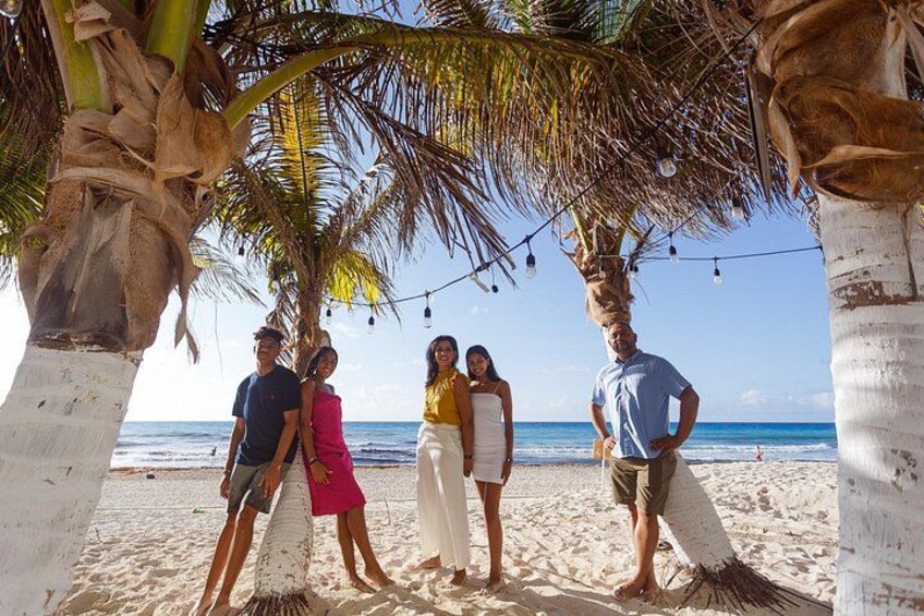 A group of people standing under palm trees on a beach with the ocean in the background. 4