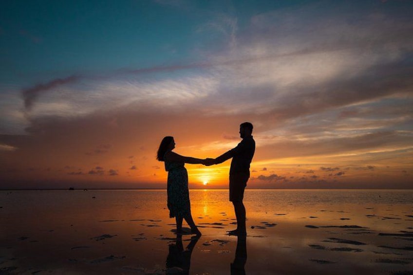 Two people holding hands on a beach at sunset. 3