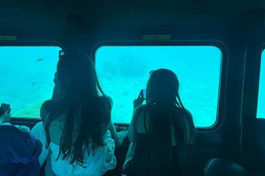 Two people sitting by a window on a boat, looking at the ocean. 5