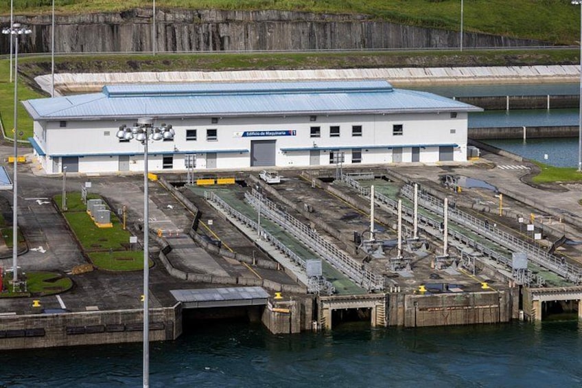 Ein großes Industriegebäude mit blauem Dach, umgeben von Wasser und einem Steg. 2