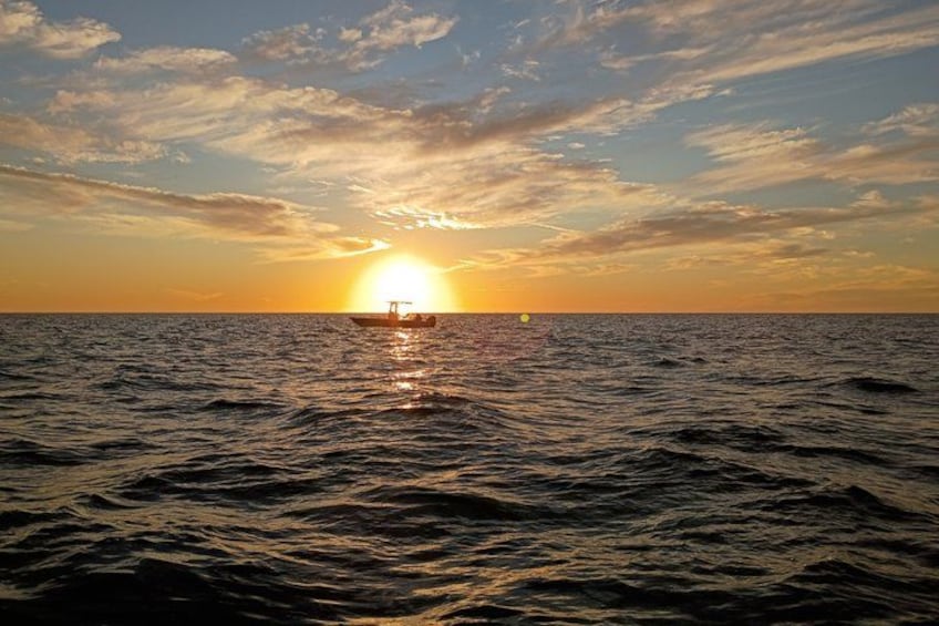 A sunset over the ocean with a boat in the distance. 3