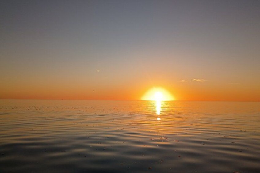 A sunset over a calm sea with a clear horizon. 2