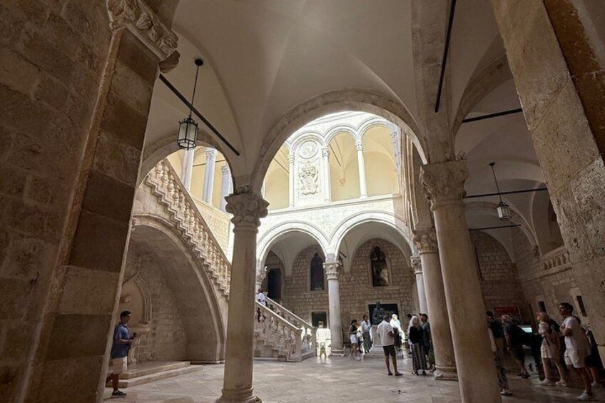 An interior courtyard with arches, columns, and a staircase. 2