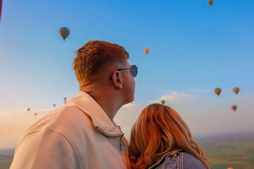 Et par der kigger på varmluftsballoner på himlen. 1