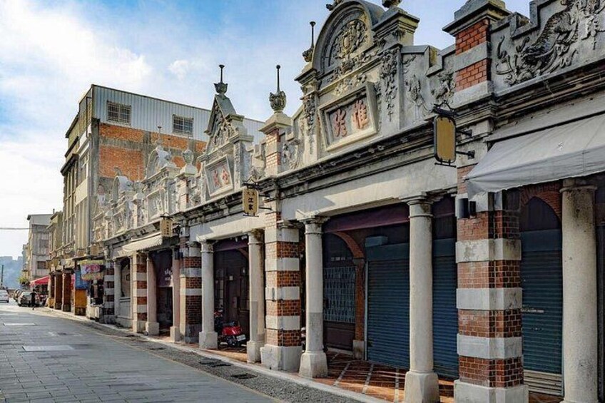 A street with ornate buildings, closed shop shutters, and a clear sky. 2