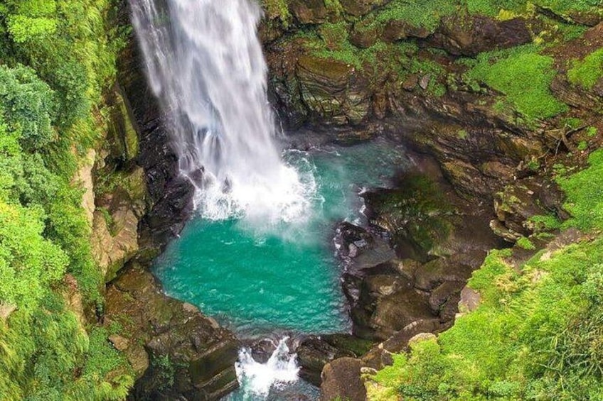 A waterfall cascading into a turquoise pool surrounded by lush green vegetation. 3
