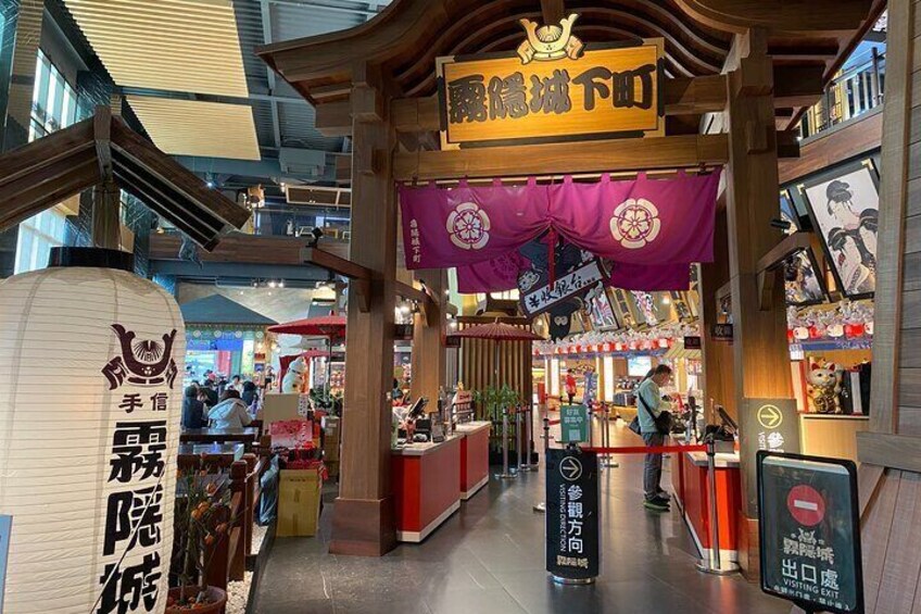 A traditional Japanese market with wooden structures and signs in Japanese. 5
