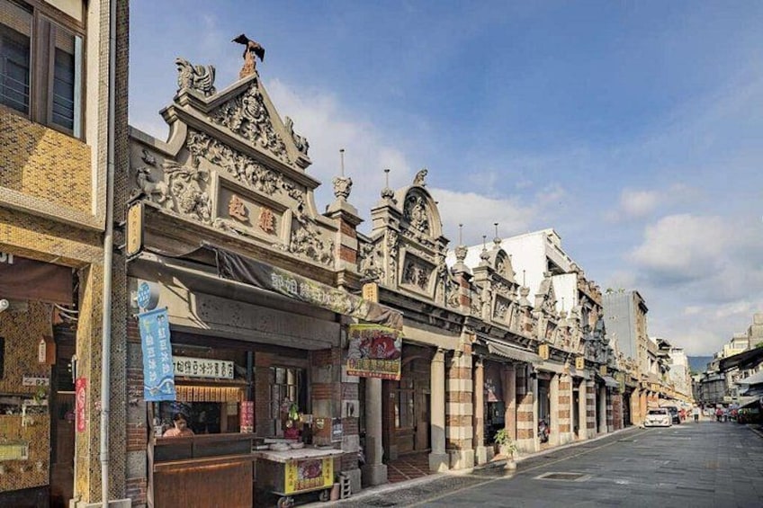 A street lined with ornate buildings, a clear sky, and a few pedestrians. 2
