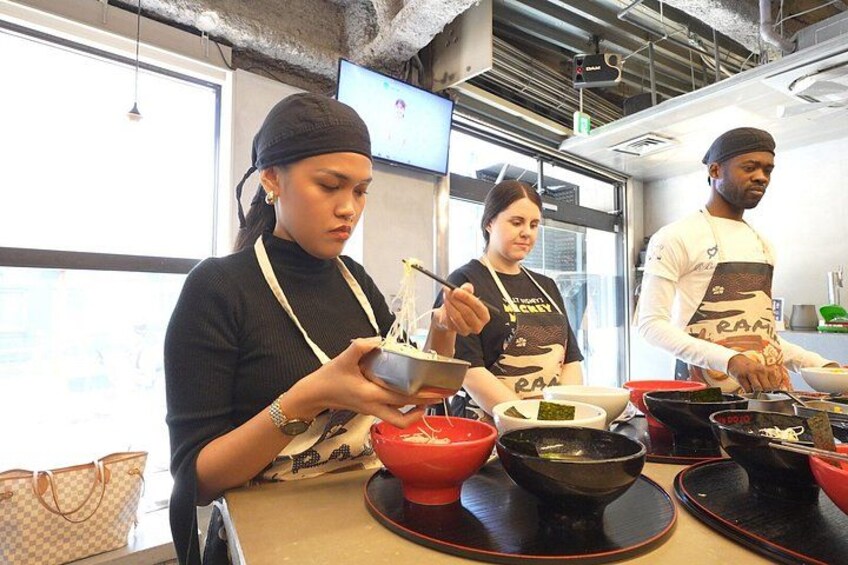 Trois personnes cuisinent dans une cuisine, entourées de divers ustensiles et ingrédients. 2