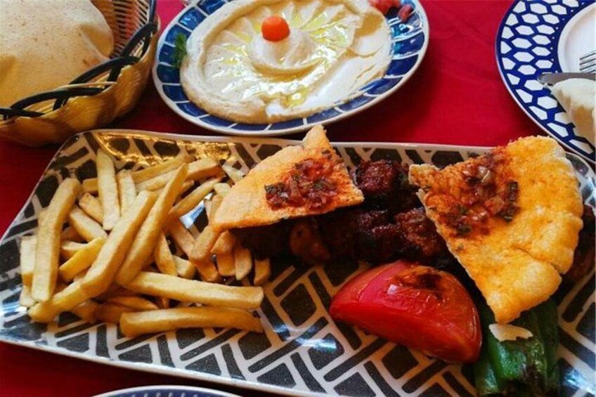 A meal with fries, meatballs, a slice of bread, and a tomato. 4