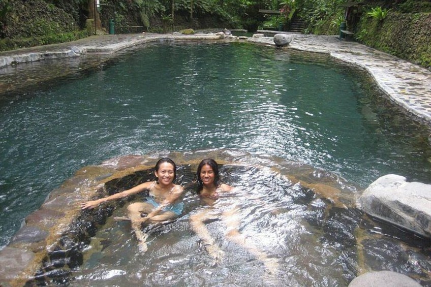 Ein natürlicher Pool mit klarem Wasser, umgeben von Steinen und viel Grün. 2