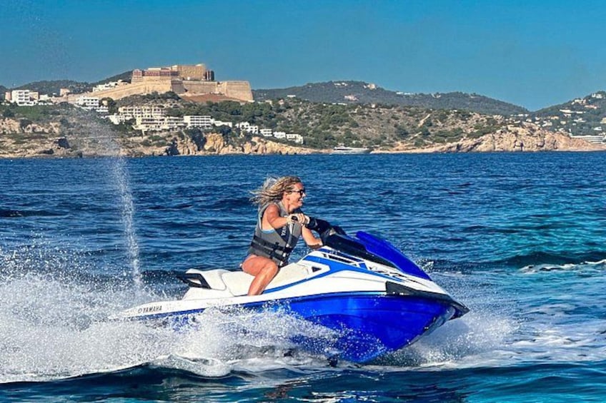 En person kører på en jetski på vandet med et kystlandskab i baggrunden. 4