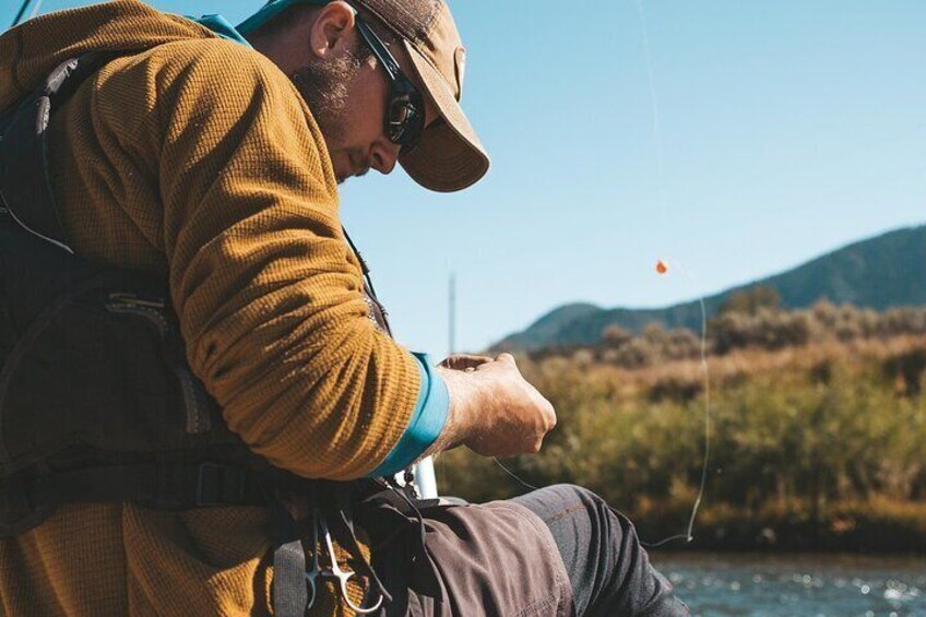 Une personne est en train de pêcher au bord d’une rivière, avec un ciel dégagé et des montagnes en arrière-plan. 5