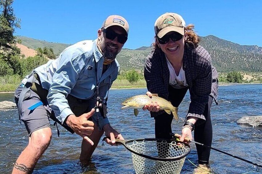 Deux personnes tenant un poisson dans une rivière. 2