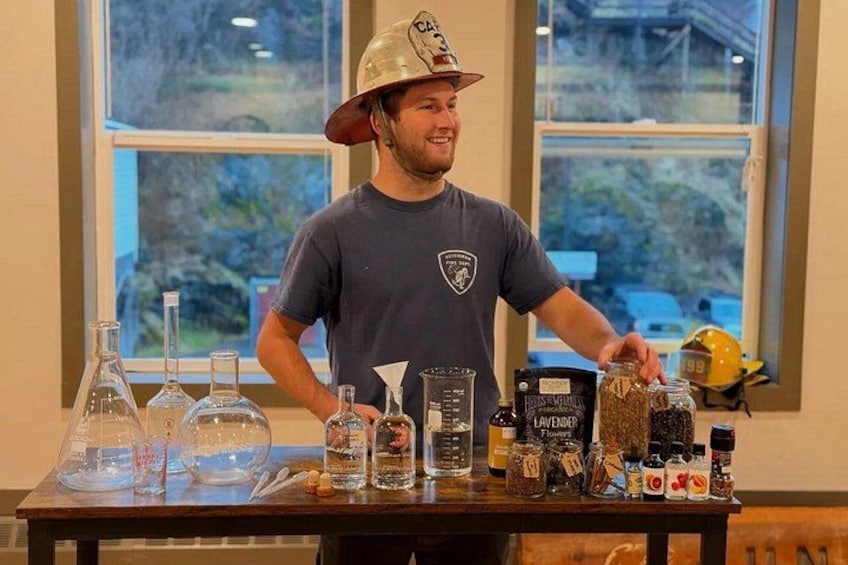 A person standing behind a table with various glass containers and jars, some labeled with names like 'Lavender' and 'Rosemary.' 4