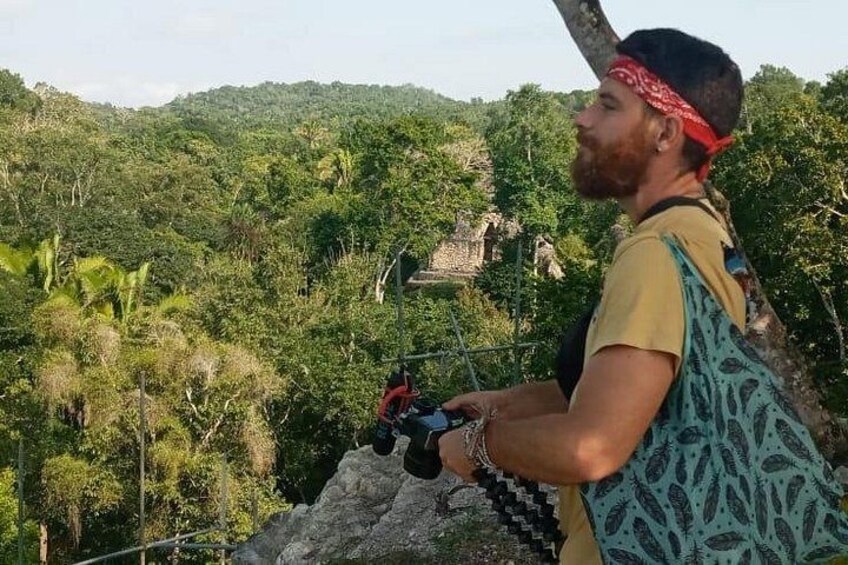 A person hiking with a backpack, overlooking a lush green landscape and ancient ruins. 3