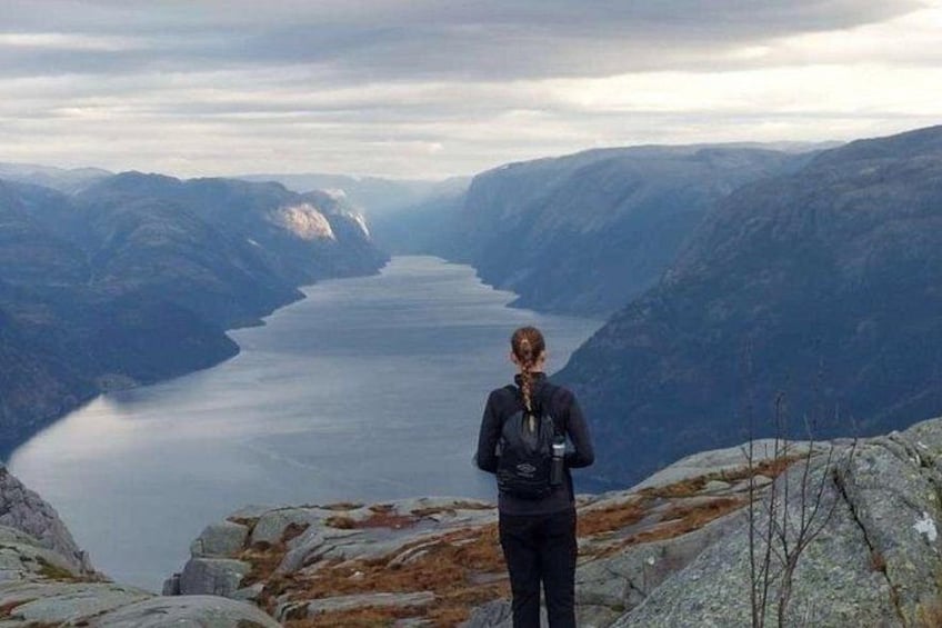 Eine Person steht auf einer Felsformation mit Blick auf einen See, der von Bergen umgeben ist. 3