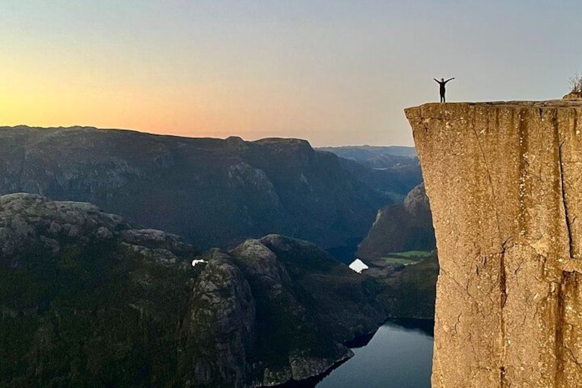 A person standing on a cliff edge with a valley below. 1