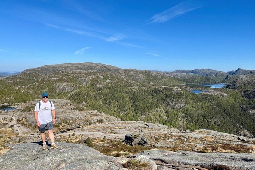 A person standing on a rocky outcrop with a mountainous landscape in the background. 2