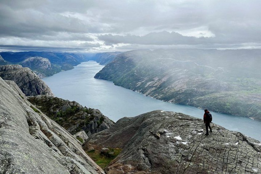 Eine Person steht auf einem Felsen mit Blick auf einen Fjord. 2