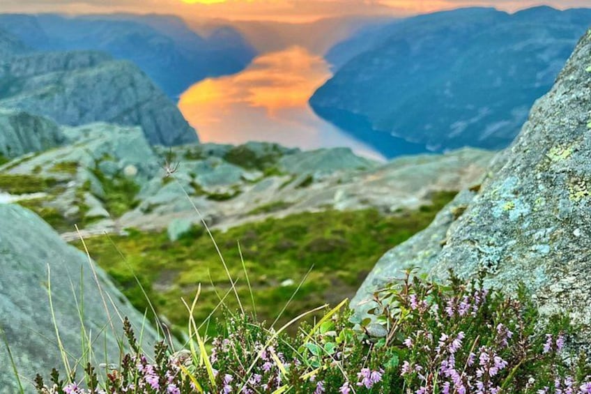 Eine Berglandschaft mit felsigem Gelände, grüner Vegetation und einem Tal mit einem Gewässer, das den Himmel spiegelt. 5
