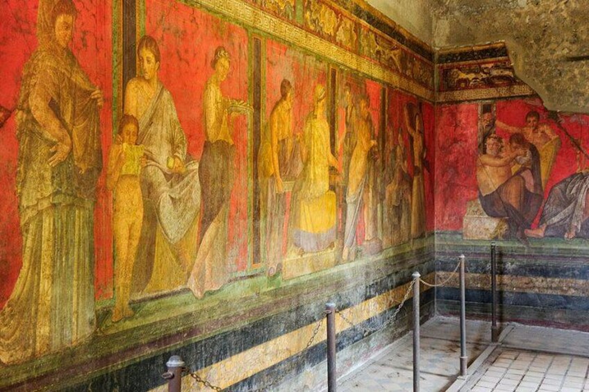 Een fresco muurschildering met figuren in klassieke kledij, een betegelde vloer en een hekwerk. 2