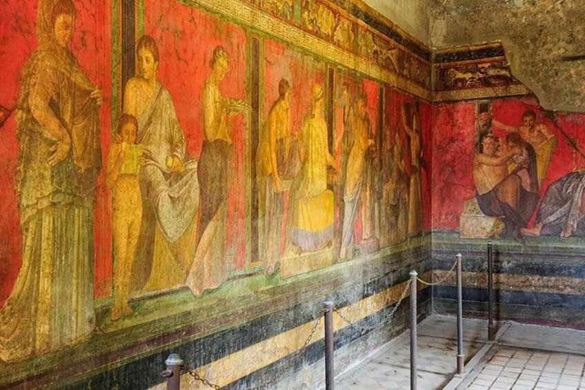 A fresco with figures in classical attire, a tiled floor, and a rope barrier. 2