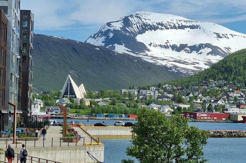 A coastal town with a mountain in the background, a modern building, and a waterfront promenade. 3