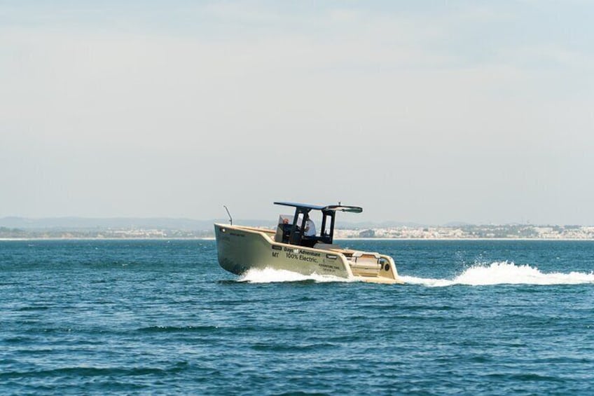 Un velero con toldo y el texto "Adventure Executive" en el costado, navegando sobre el agua. 2