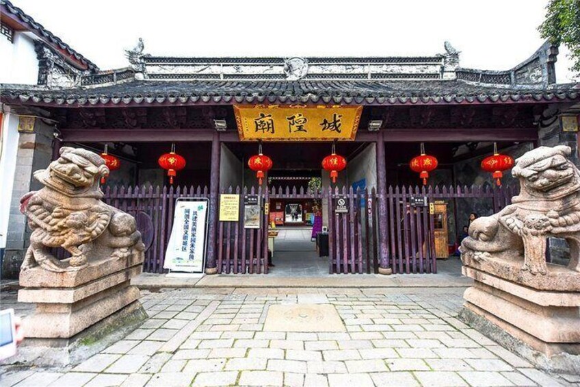 Ein traditionelles chinesisches Tor mit Steinstatuen von Löwen, einem gelben Schild und roten Laternen. 5