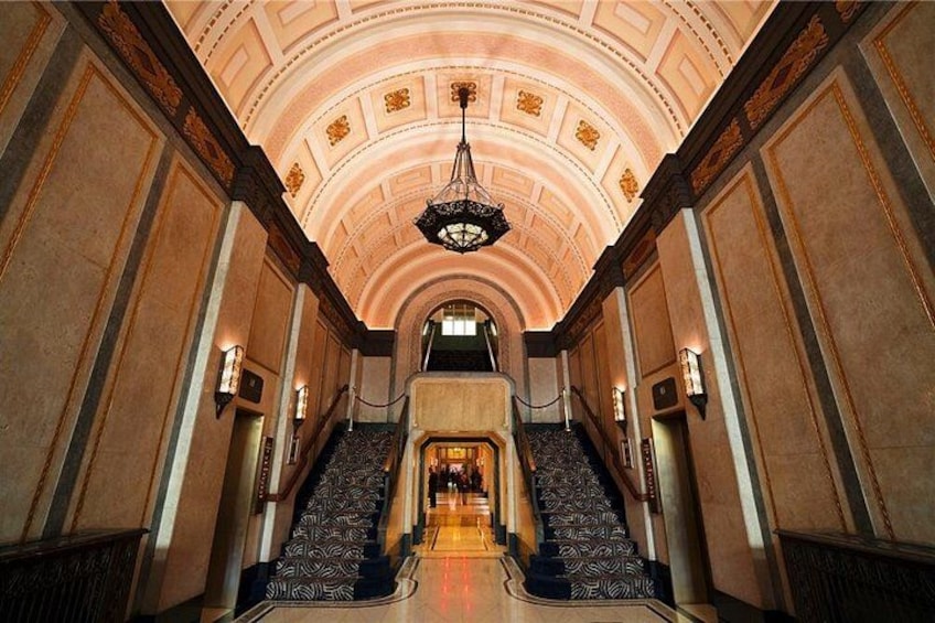 Ein prachtvolles Interieur mit hoher, gewölbter Decke, aufwendigen Treppenhäusern und einem zentralen Kronleuchter. 3