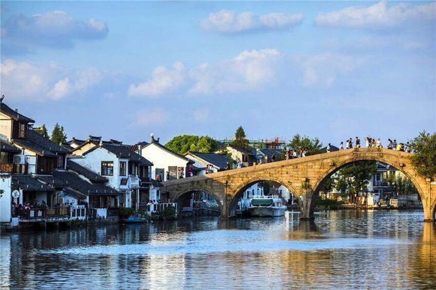 Eine Stebrücke über einem Fluss mit traditionellen Gebäuden auf der linken Seite. 4
