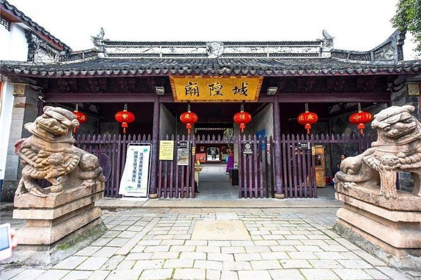 Ein traditionelles chinesisches Tor mit Steinstatuen von Löwen, roten Laternen und einem gelben Schild. 4