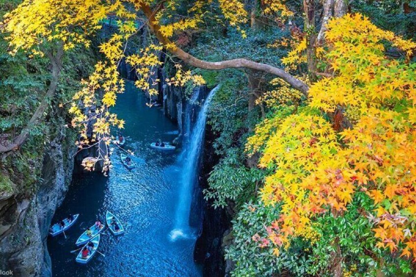 Ein Fluss mit einem Wasserfall, umgeben von Bäumen mit gelben Blättern. 1