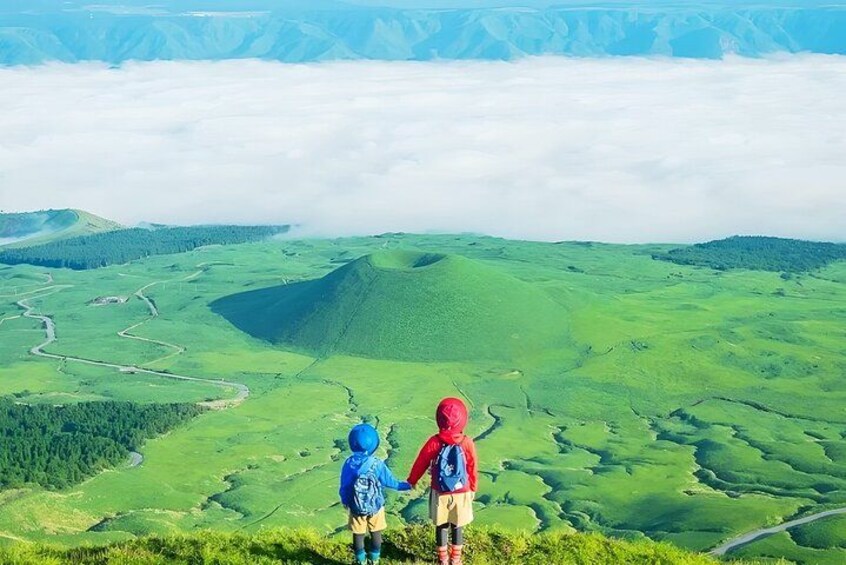 Deux randonneurs se trouvent sur un sentier de montagne, d’où l’on aperçoit une vallée verdoyante, avec des champs et une route sinueuse. 3