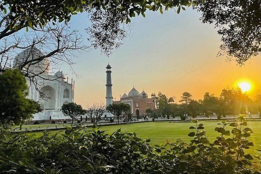 Il Taj Mahal, un'imponente mausoleo in marmo bianco, con un minareto e una moschea sullo sfondo, sotto un cielo sereno. 5
