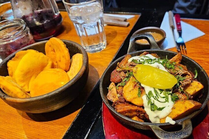 A meal with fried plantains, a skillet with meat and a yellow slice on top, and a bowl of plantains. 4