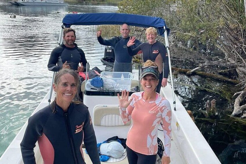 A group of people on a boat near a riverbank with trees. 1