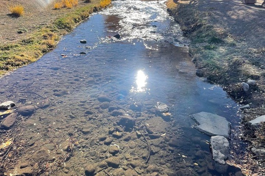 A clear stream with rocks and sunlight reflecting on the water. 3