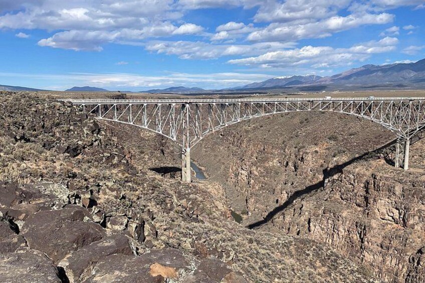 A bridge over a rocky canyon with a clear sky. 2