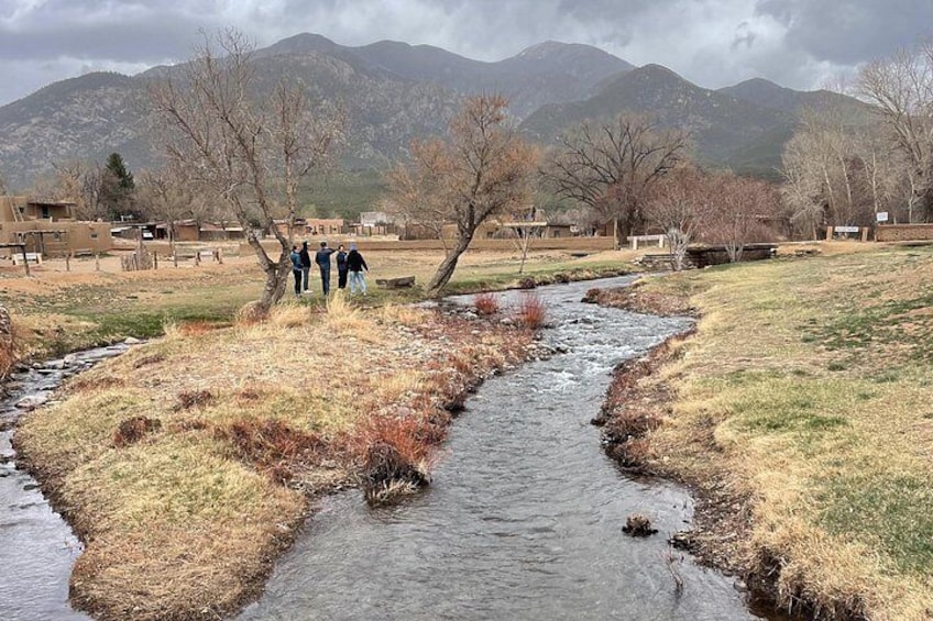 A stream, a group of people, and mountains in the background. 2