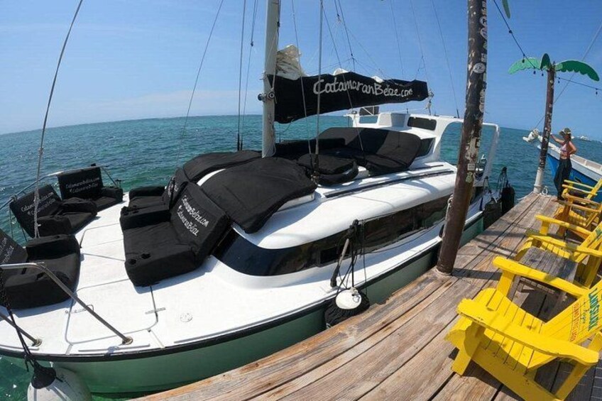 A boat docked at a wooden pier with a clear view of the ocean. 5