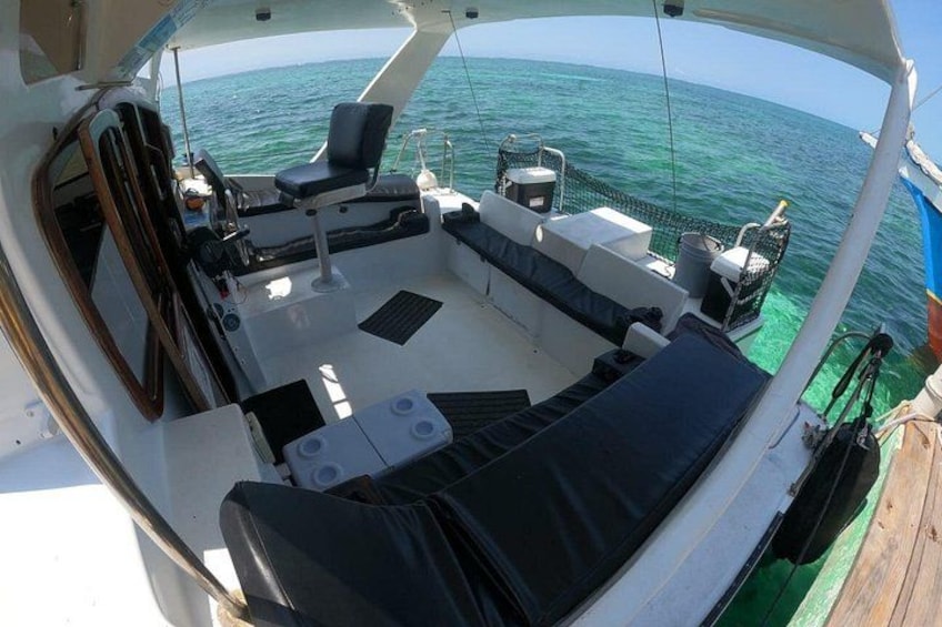 A boat's deck with seating, a steering wheel, and a view of the ocean. 4